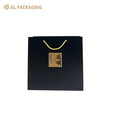 Matte schwarze Papiertragetasche mit individuellem Logo, Kraft-Kalligrafie-Aufklebern und gedrehten goldenen Kordelgriffen für eine umweltfreundliche Geschenkverpackung